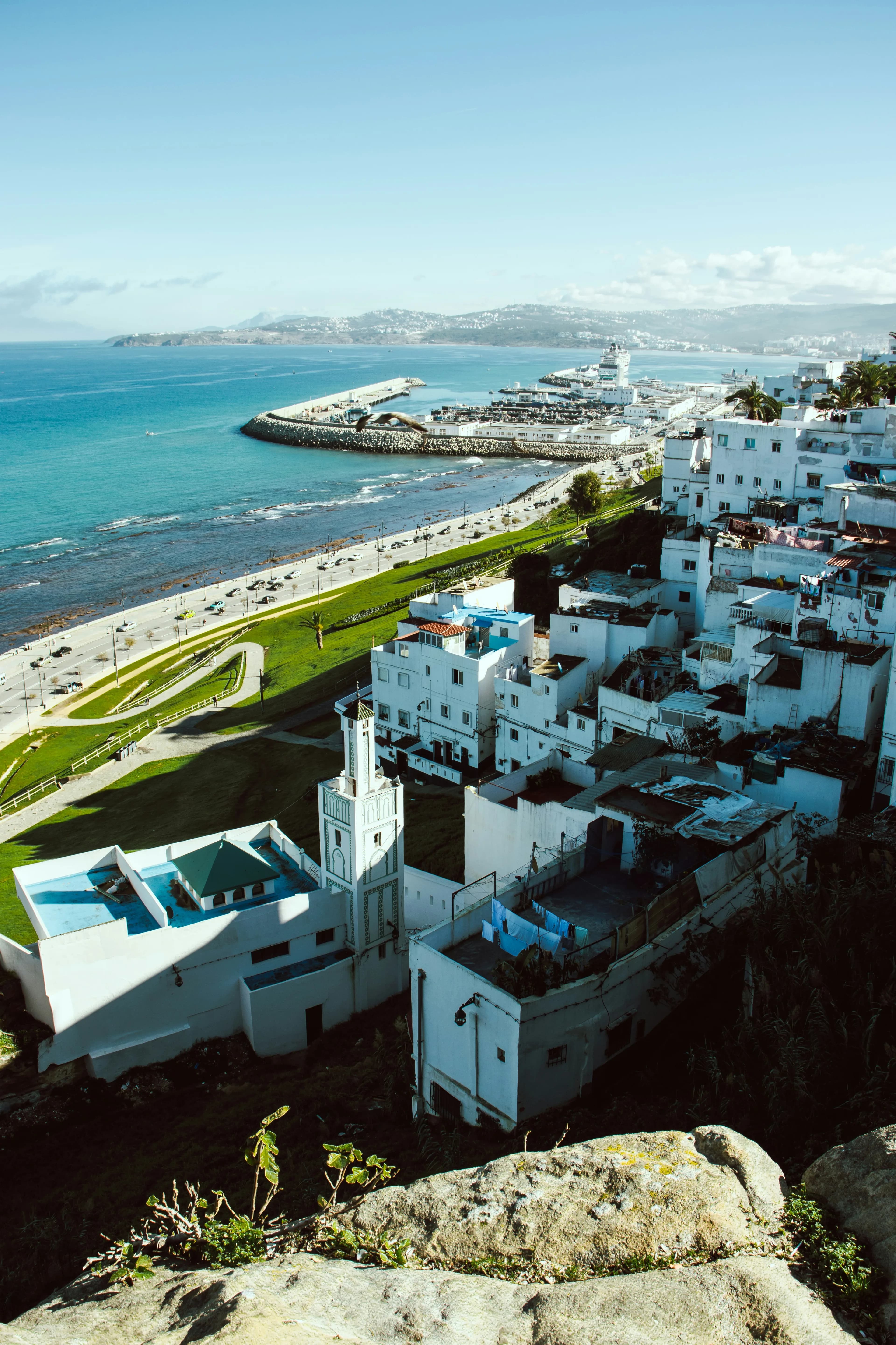 White medina buildings and a minaret overlooking Tangier's blue sea and harbour
